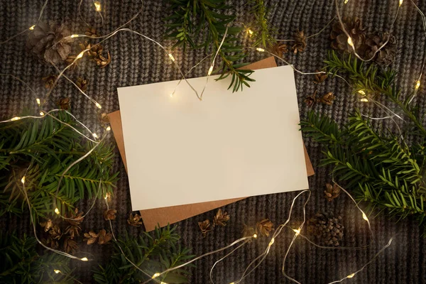 Blanco papier voor het schrijven van een brief aan de Kerstman. Donkere achtergrond van een gebreide sjaal met een lichtgevende slinger — Stockfoto