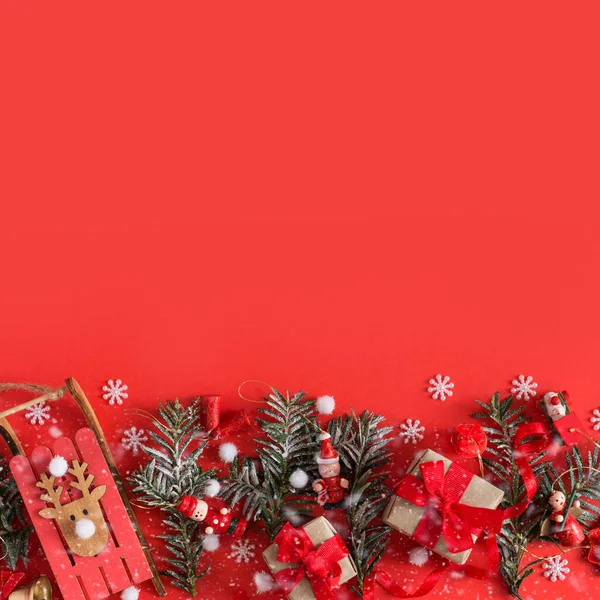 Noel oyuncakları, hediye kutusu, kurdeleler ve kırmızı arka planda kar taneleri. — Stok fotoğraf