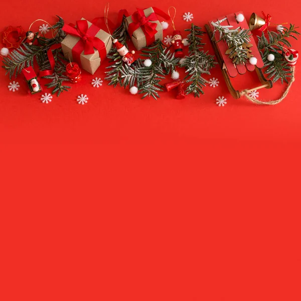 Borde navideño de juguetes, caja de regalo, cintas y copos de nieve sobre fondo rojo —  Fotos de Stock