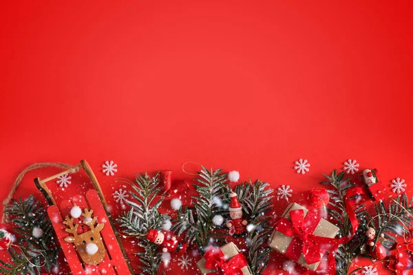 Borda de Natal de brinquedos, caixa de presente, fitas e flocos de neve em fundo vermelho — Fotografia de Stock