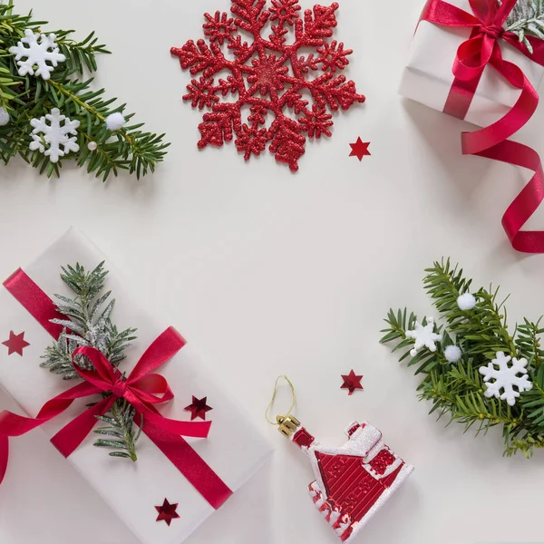 Frame made of christmas gifts with red ribbons, pine branches, toys on white background — Stock Photo, Image