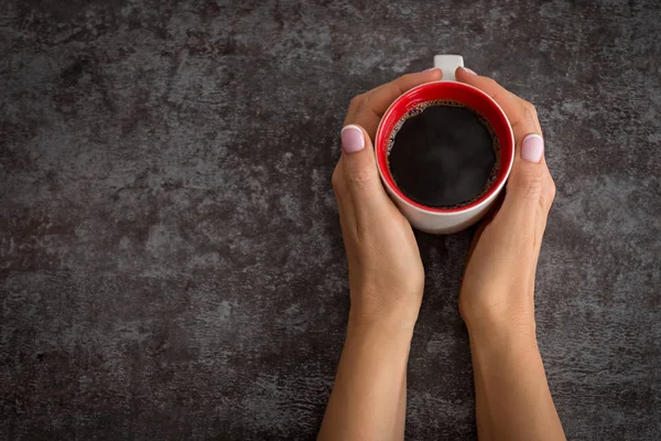 Tangan wanita memegang cangkir kopi di atas meja gelap — Stok Foto