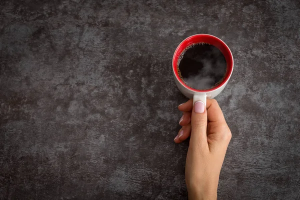 Tangan wanita memegang cangkir kopi di atas meja gelap — Stok Foto
