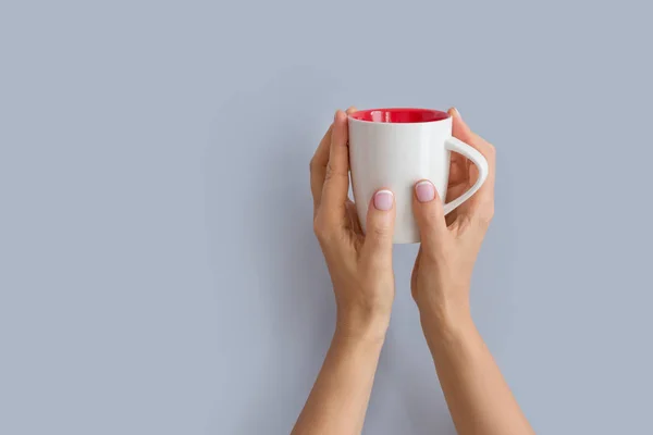 Frauenhände, die eine weiße Tasse hochhalten — Stockfoto