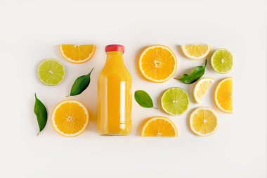 Taze sıkılmış meyve suyu şişede, dağınık narenciye meyveleri masada.