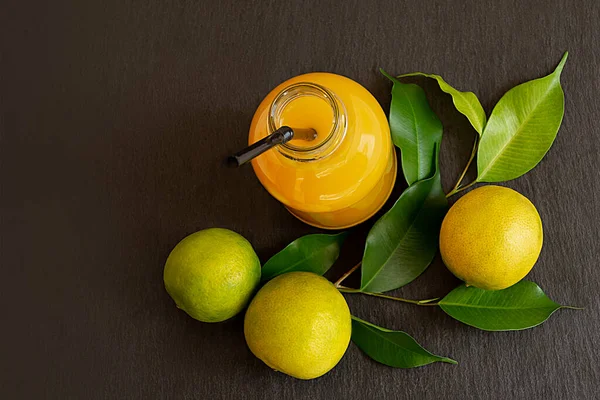 Taze limon ve koyu taştan bir arka planda meyve suyu şişesi. — Stok fotoğraf