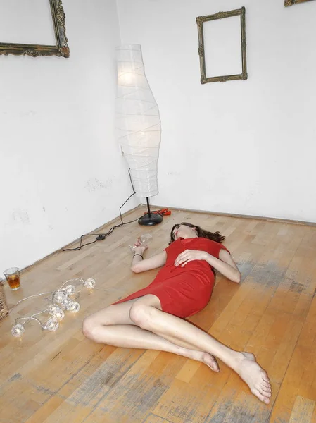 Mujer en vestido rojo acostada en el suelo con cristal de la victoria —  Fotos de Stock