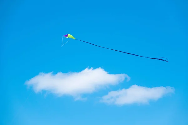 Чайлдс игрушечный змей, летящий в ясном голубом летнем небе — стоковое фото