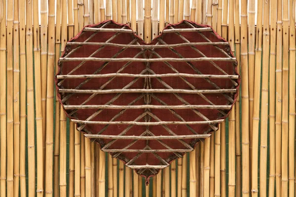 Coeur en bois fait main sur un mur de bambou Images De Stock Libres De Droits