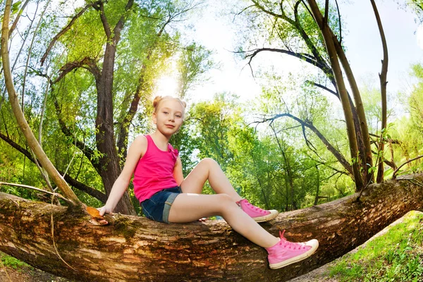 Girl sitting on tree trunk — Stock Photo, Image