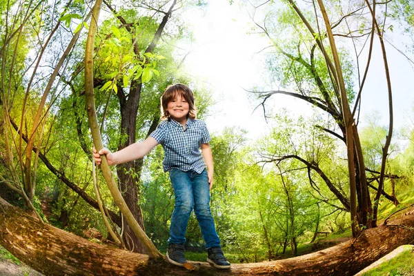 Chico divirtiéndose en caído árbol — Foto de Stock