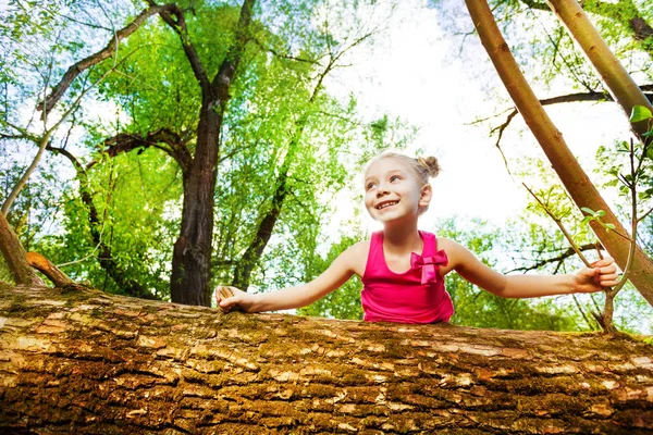 Chica espiando detrás de árbol caído — Foto de Stock