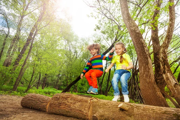 Kinder springen über Baumstamm — Stockfoto