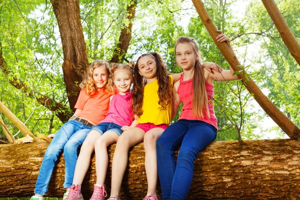 Девушки сидят на упавшем дереве — стоковое фото