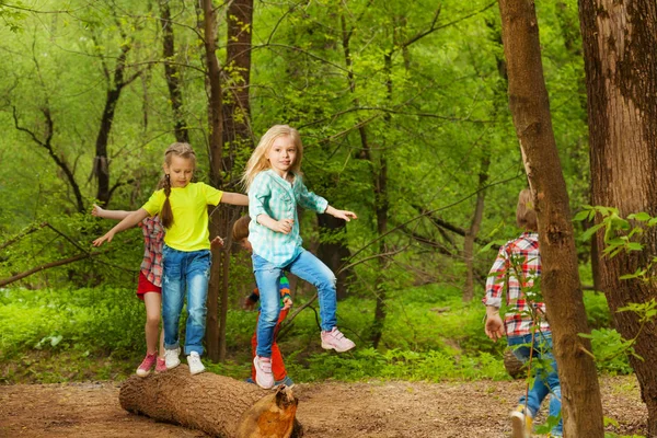 Kids balancing on log in forest — Stock Photo, Image
