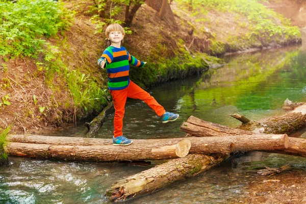 Mignon garçon traversant rivière — Photo