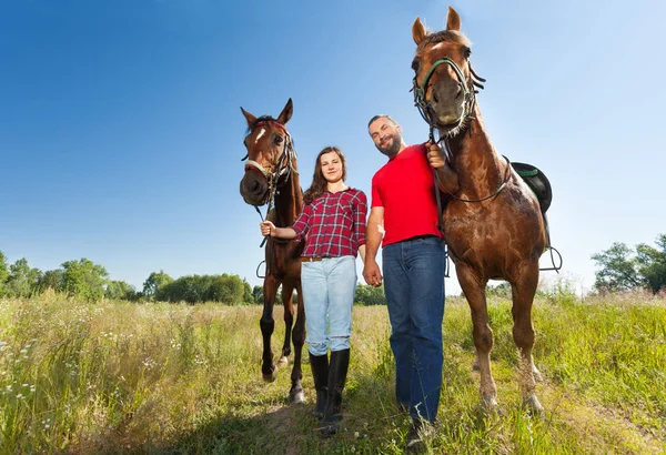 Casal andando com cavalos — Fotografia de Stock