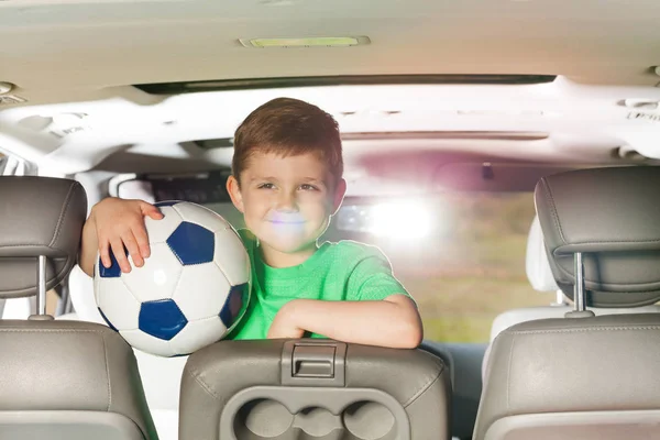 Boy holding soccer ball in car — Stock Photo, Image