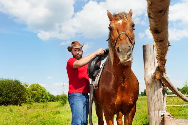 Cowboy ensillando caballo marrón —  Fotos de Stock