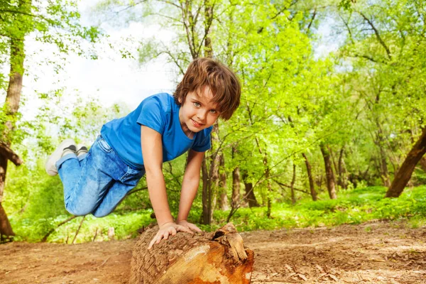 Junge springt über Baumstamm — Stockfoto