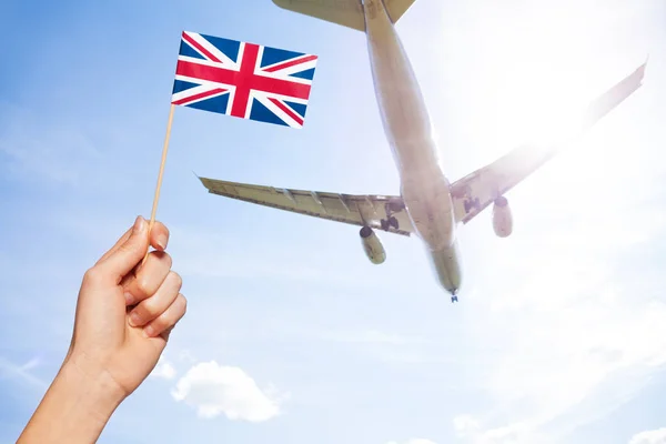 Britisk flag mod fly, der flyver - Stock-foto