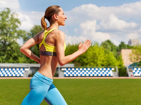 Young woman running at stadium tracks — Stock Photo, Image