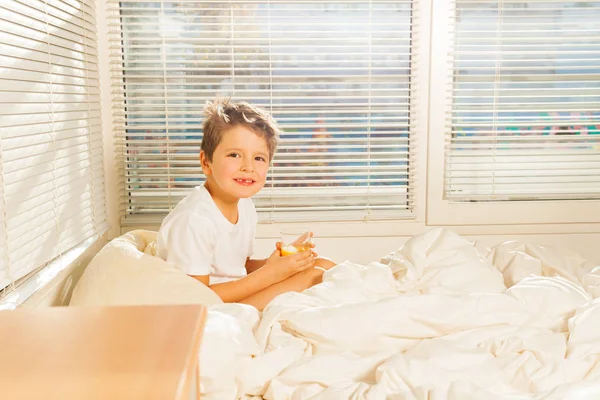 Μικρό αγόρι πίνοντας χυμό στο κρεβάτι — Φωτογραφία Αρχείου