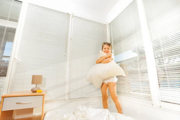 Pequeño niño saltando sobre malo con almohada —  Fotos de Stock