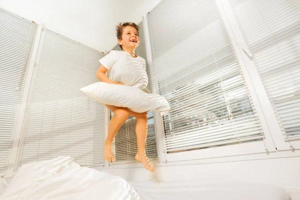 Little boy jumping on bad with pillow — Stock Photo, Image