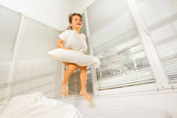 Piccolo ragazzo saltando su male con cuscino — Foto Stock