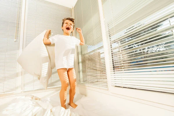 Pequeño niño saltando sobre malo con almohada —  Fotos de Stock