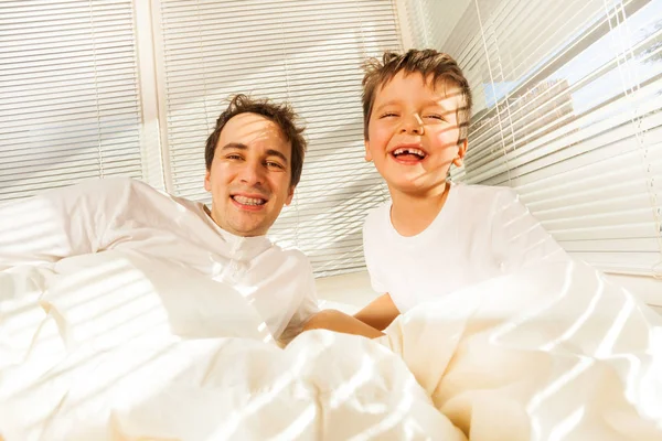 Отец и мальчик, просыпающиеся в постели — стоковое фото