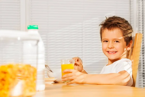 Хлопчик їсть зернові та п'є сік — стокове фото