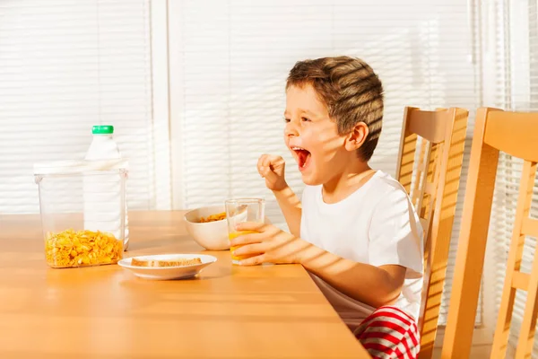 男孩吃谷类食物和喝果汁 — 图库照片