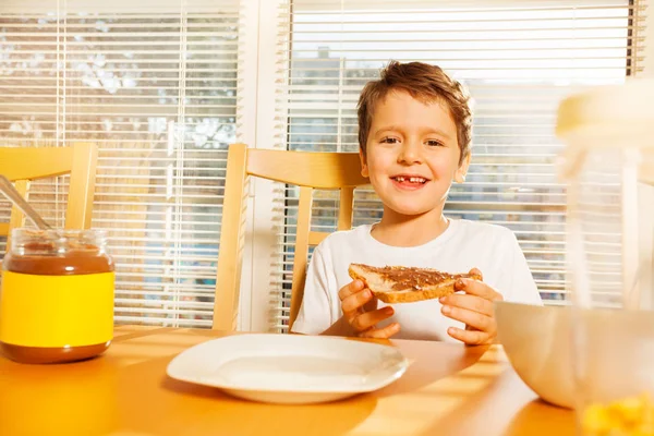 Мальчик ест тосты с шоколадом распространение — стоковое фото