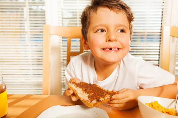 チョコスプレッドとトーストを食べる少年 — ストック写真