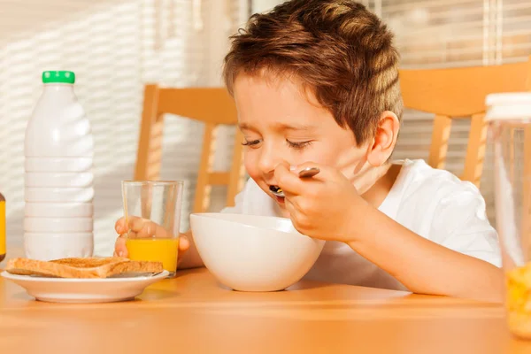 Junge isst Getreide und trinkt Saft — Stockfoto