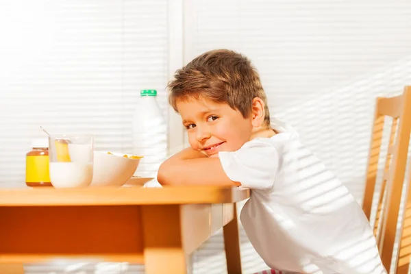 Мальчик сидит за столом во время завтрака — стоковое фото