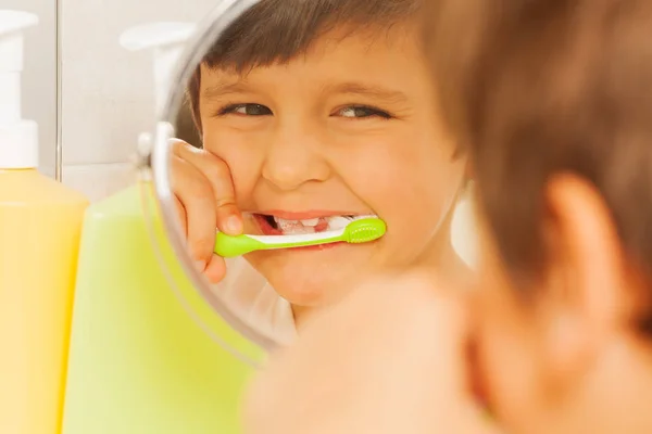 Мальчик в зеркале во время чистки зубов — стоковое фото