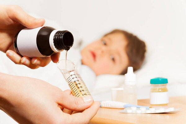 Женщина наливает антипиретический сироп

