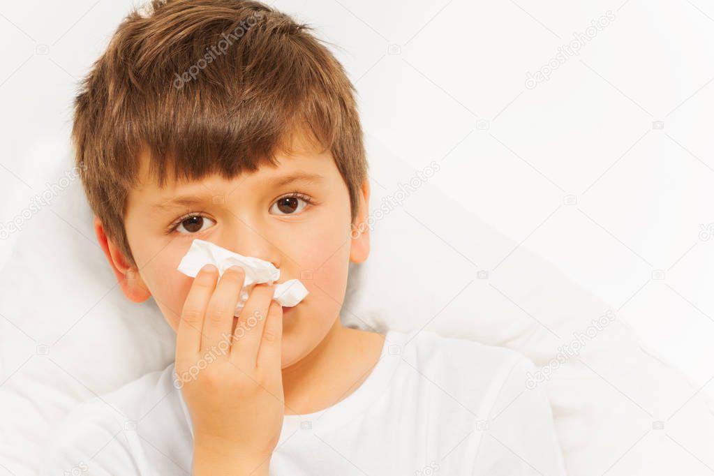 Sick boy blowing nose