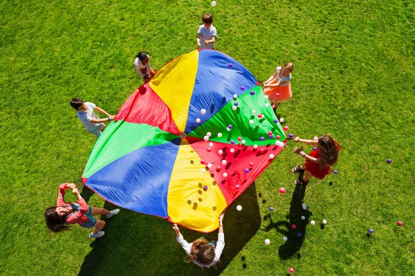Glückliche Kinder mit buntem Fallschirm — Stockfoto