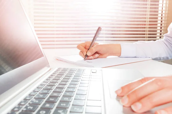 Vrouw met behulp van laptop en het maken van notities — Stockfoto