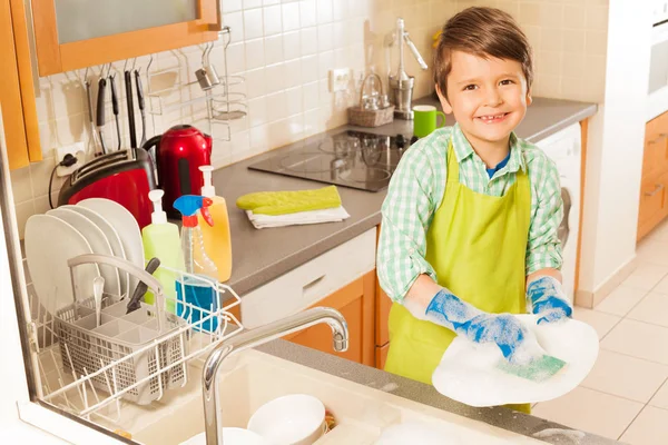 Dish washing concept. Child boy washing the dishes in the kitchen