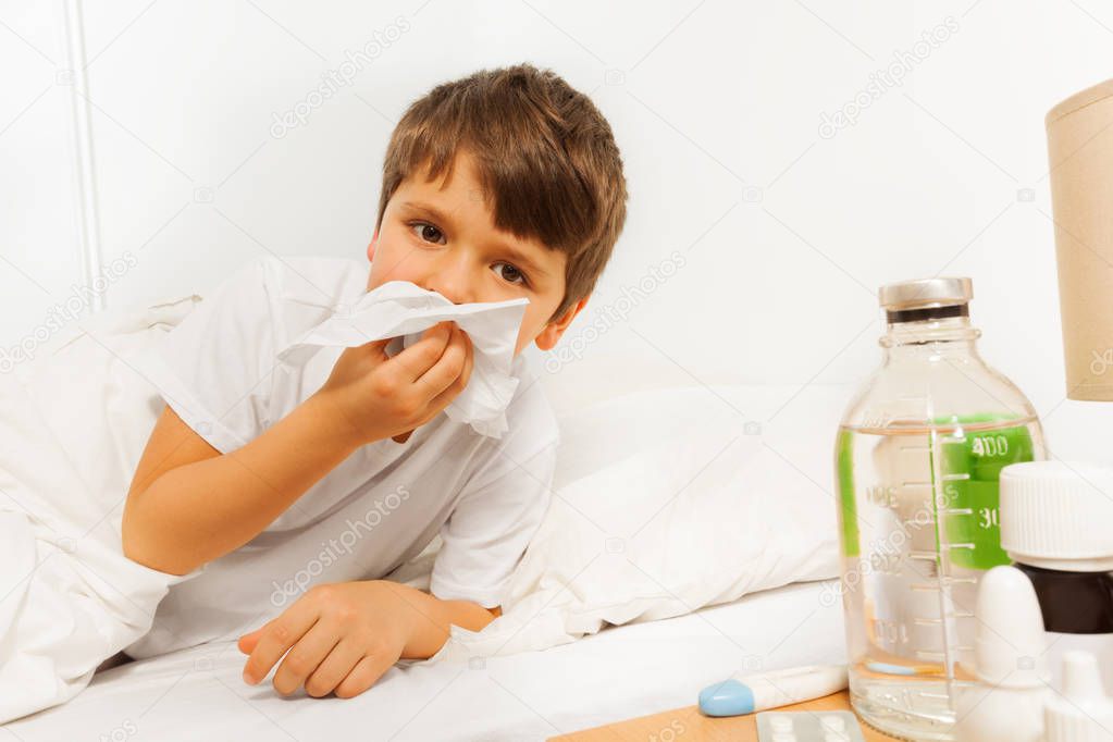 Sick boy blowing nose