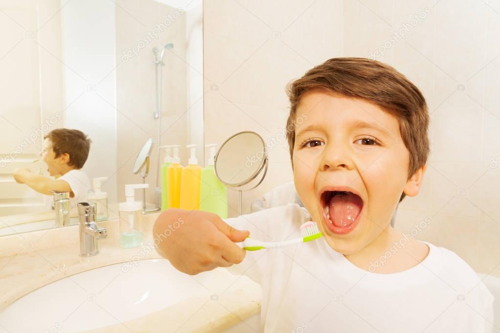 boy in mirror during tooth brushing