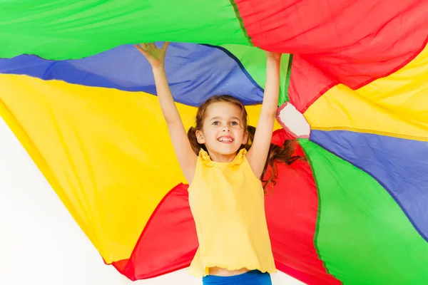 Meisje onder gekleurde parachute springen — Stockfoto