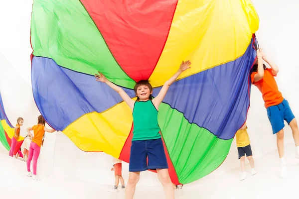 Niño bajo paracaídas de colores — Foto de Stock