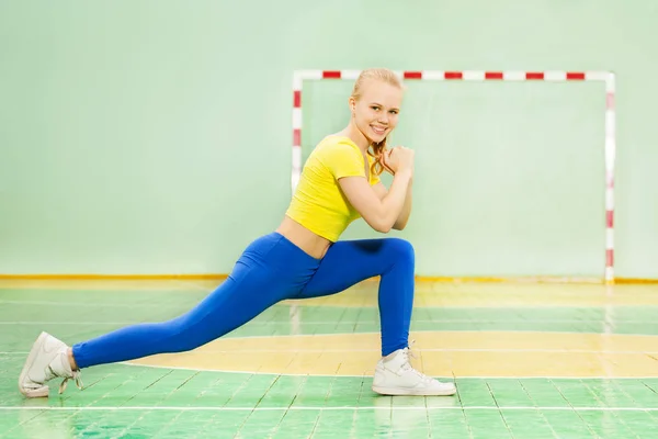 Blonde girl performing forward lunge — Stock Photo, Image