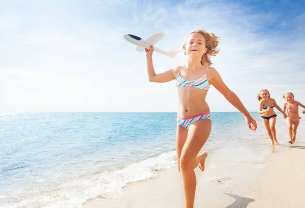 Mädchen läuft mit Flugzeugmodell am Strand — Stockfoto